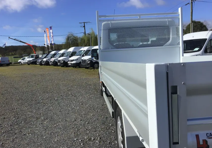 Vue arrière droite d'un Ford Transit Chassis Cabine blanc avec plateau 4 mètres et ridelles en aluminium.