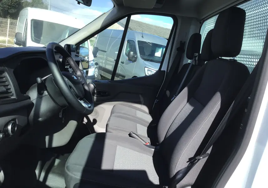 Vue intérieure côté conducteur du Ford Transit Chassis Cabine blanc, montrant les sièges avant et le volant.