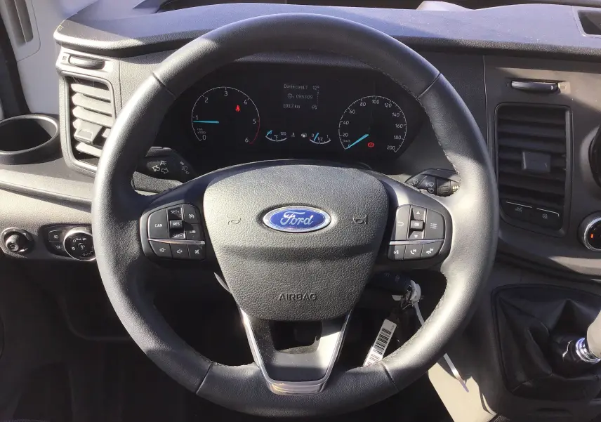 Vue rapprochée du volant noir du Ford Transit Chassis Cabine 2020 avec tableau de bord et levier de vitesses manuel visible.
