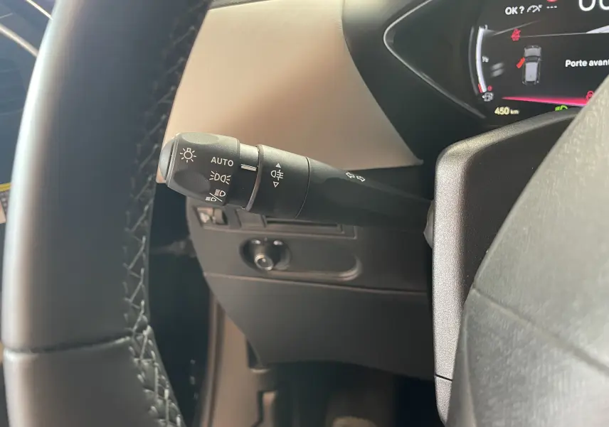 Gros plan sur la manette de phares à gauche du volant du DS3 Crossback 2024 en intérieur beige et noir.