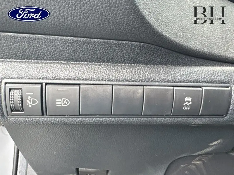 Panneau de commandes noires avec réglage des phares et bouton de contrôle de stabilité dans l'habitacle d'une Toyota Corolla gris Manhattan.