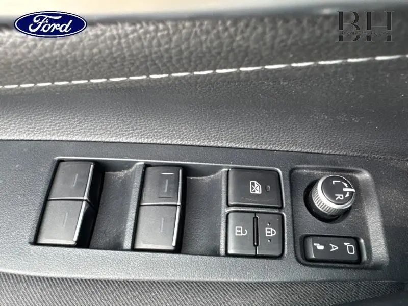 Gros plan sur les commandes des vitres et rétroviseurs côté conducteur d'une Toyota Corolla gris Manhattan métallisé.