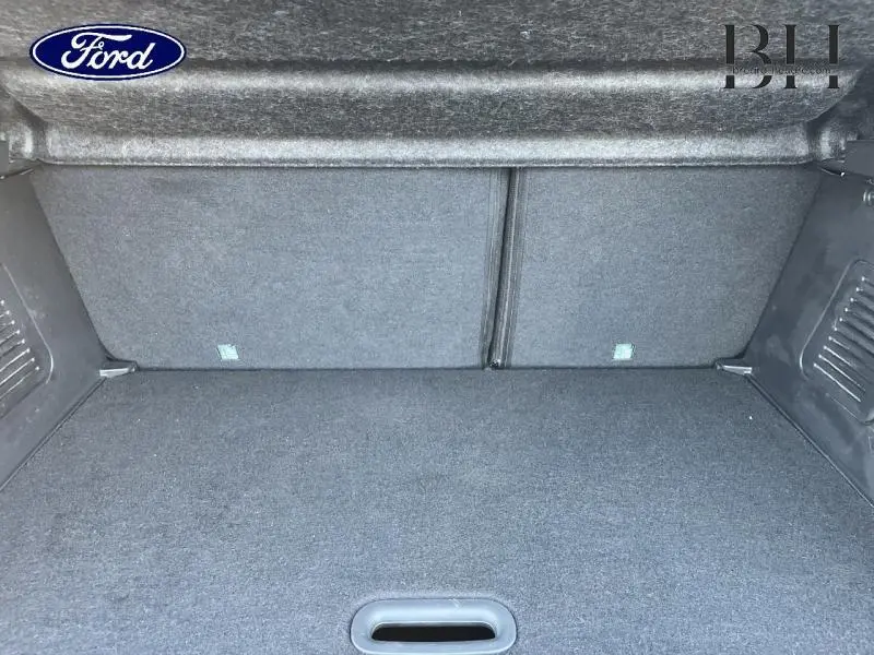 Coffre vide en tissu gris d'un véhicule, vue intérieure arrière montrant la banquette rabattue.