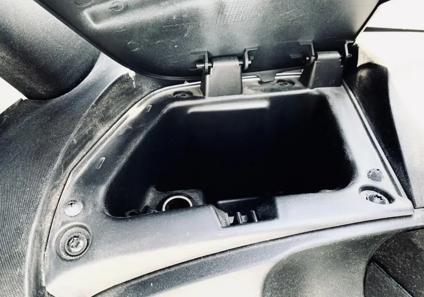 Gros plan sur la boîte à gants ouverte côté droit de la Renault Twizy blanche, montrant l'intérieur vide et la texture noire.