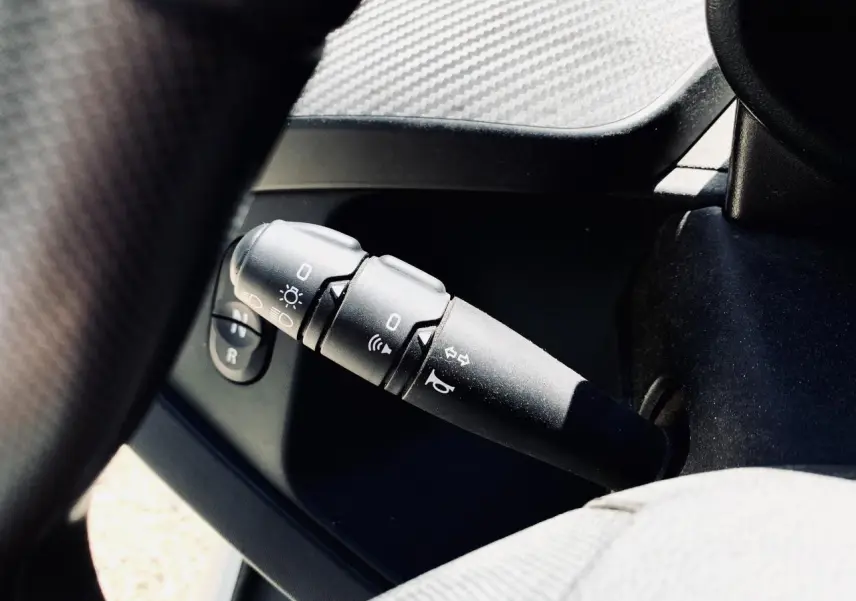 Gros plan sur la commande de clignotants et phares à gauche du volant dans l’habitacle blanc du Renault Twizy Intens 2019.