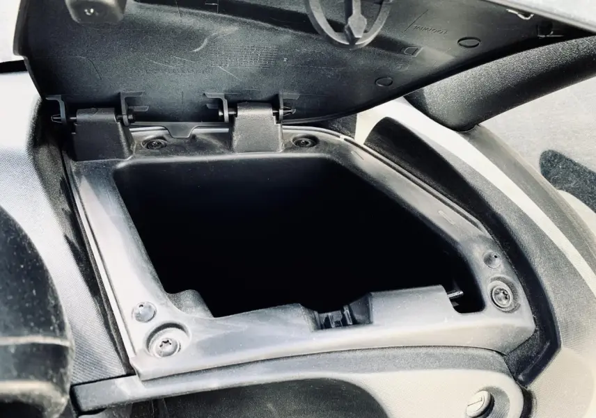 Gros plan sur la boîte à gants droite ouverte du Renault Twizy blanc, montrant l'intérieur vide et la charnière.
