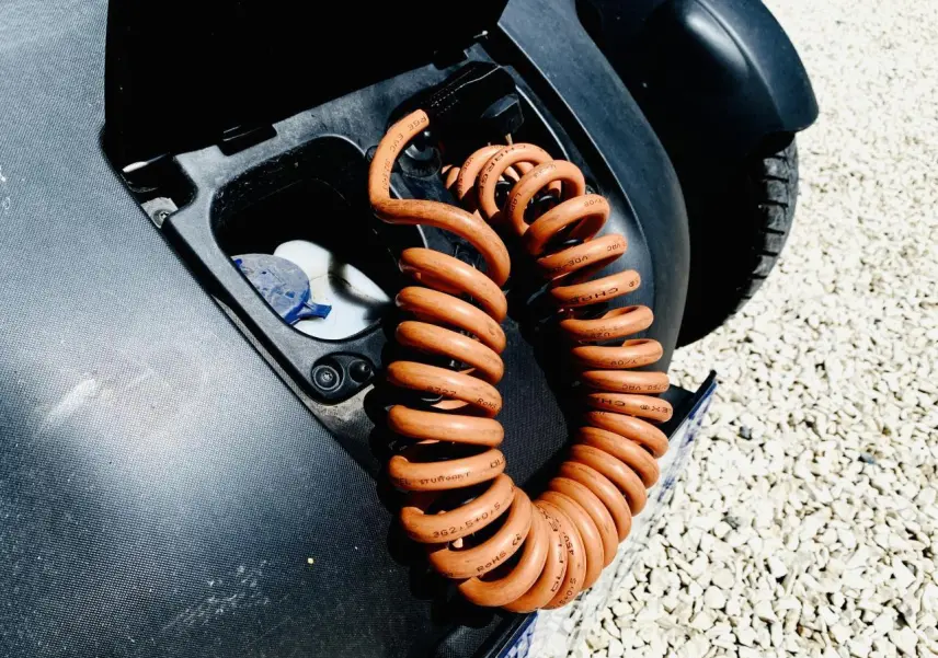 Gros plan sur le câble de charge orange enroulé dans la trappe de recharge d’une Renault Twizy blanche, vue arrière droite.