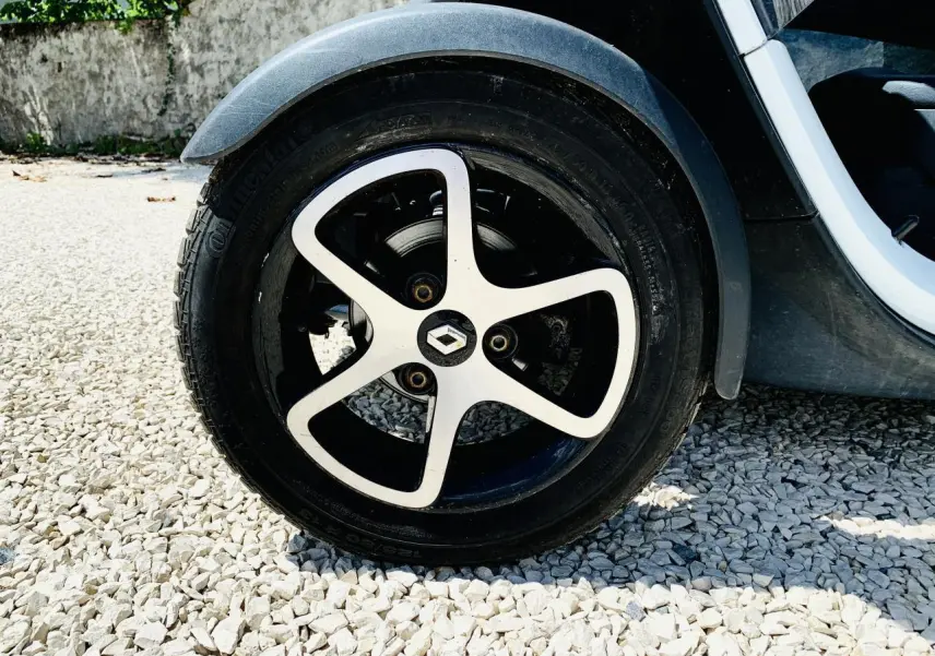 Gros plan sur la roue arrière droite blanche d'une Renault Twizy 2019, avec jante noire et argentée au design distinctif.