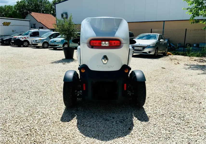 Vue arrière d'une Renault Twizy blanche électrique, avec feu arrière ovale rouge et logo Renault visible.