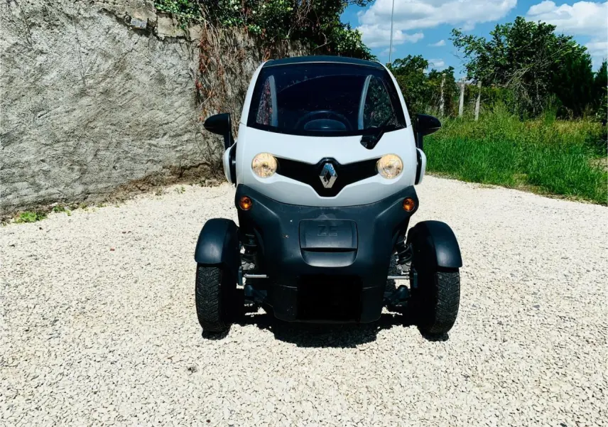 Vue frontale d'une Renault Twizy blanche électrique 2019, avec phares allumés et logo Renault bien visible.