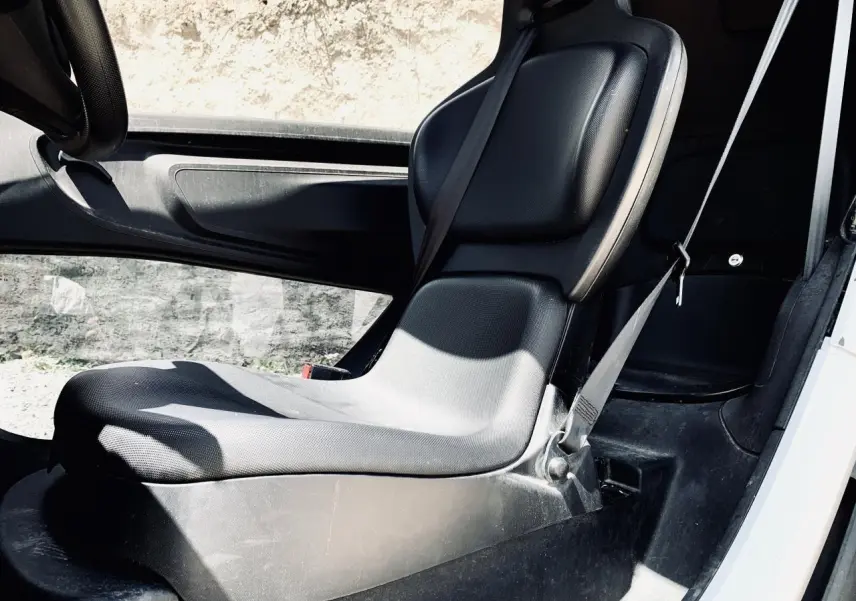 Vue intérieure côté droit du siège avant noir du Renault Twizy blanc avec ceinture de sécurité visible.
