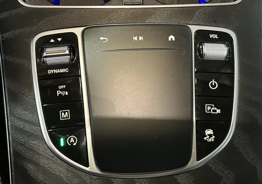 Gros plan sur la console centrale tactile du Mercedes GLC 220D AMG Line, avec commandes de volume et mode dynamique.