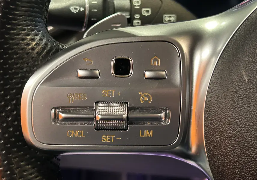 Gros plan sur les commandes de régulateur de vitesse au volant cuir noir du Mercedes GLC 220D AMG Line 2021.