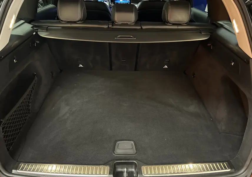 Coffre spacieux vu de l'arrière d'un Mercedes GLC 220D AMG Line noir Obsidienne avec banquette arrière et filet de rangement.