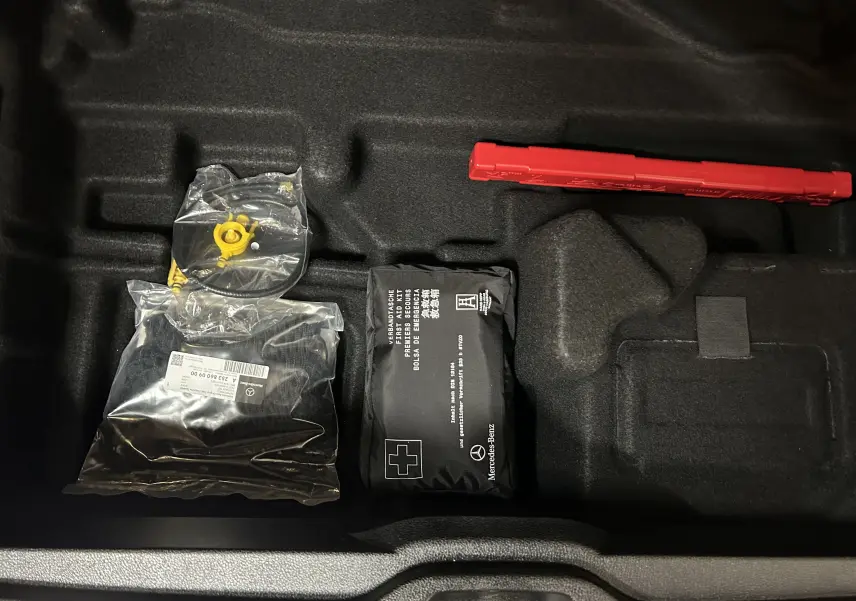 Vue rapprochée du coffre d’un Mercedes GLC 220D AMG Line 2021 montrant kit de secours et triangle de signalisation rouge.