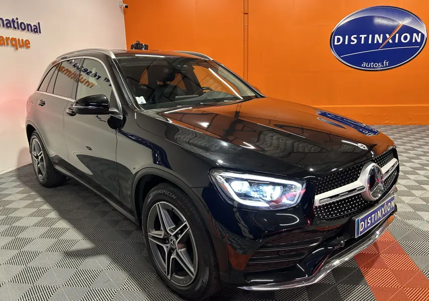 Mercedes GLC 220D AMG Line noir Obsidienne métallisé, vue 3/4 avant droit avec phares allumés en intérieur showroom.