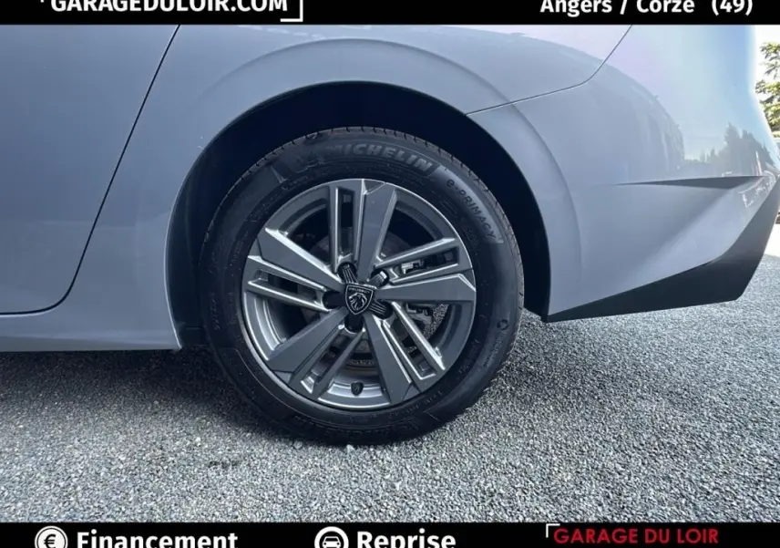 Gros plan sur la roue arrière droite gris clair d'une Peugeot 308 2023 avec jante alliage au design moderne.