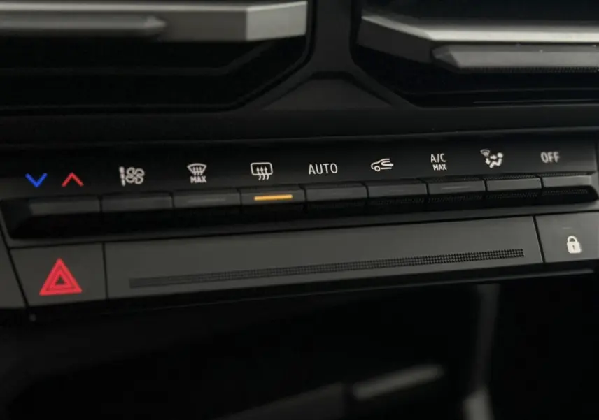 Détail de la console centrale du Dacia Duster 2026, montrant les commandes de climatisation et les boutons de sécurité.