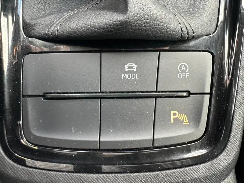 Gros plan sur les boutons de commande du mode de conduite et du parking assisté dans une Skoda Scala gris argenté.
