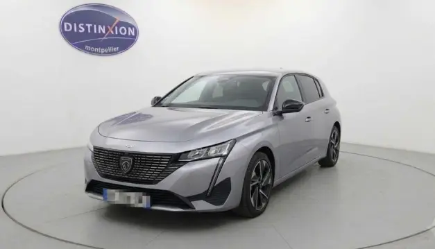 Peugeot 308 PHEV 180 e-EAT8 Allure gris clair vue 3/4 avant, avec calandre noire et feux LED distinctifs.