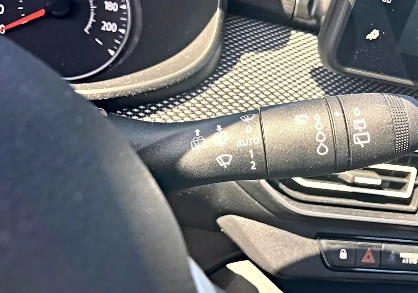 Gros plan sur la commande d’essuie-glace à gauche du volant dans l’habitacle noir de la Dacia Sandero 2025.