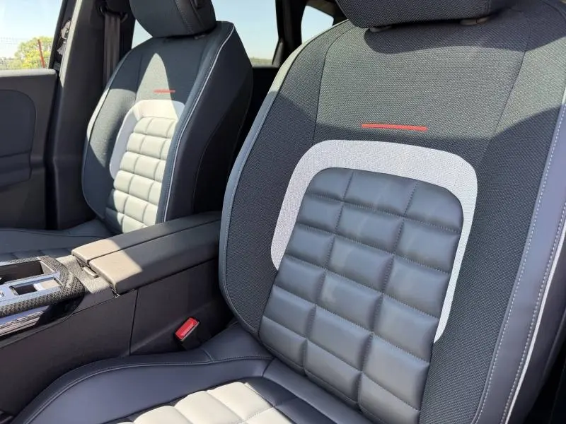 Gros plan sur les sièges avant du Citroën C5 Aircross 2026, tissu bleu et cuir noir avec surpiqûres rouges.