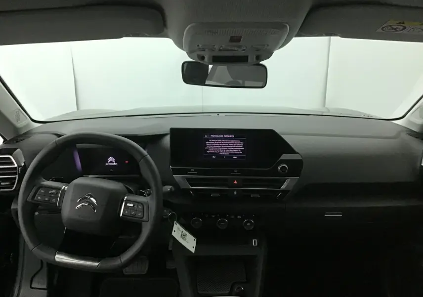 Intérieur noir du Citroën C4 2022 vu de face, tableau de bord moderne avec écran tactile central allumé.