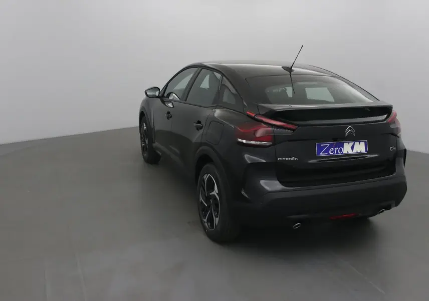 Vue 3/4 arrière droite d'une Citroën C4 noire 2022 avec toit plongeant et feux arrière distinctifs en forme de boomerang.