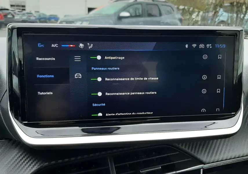 Écran tactile central de la Peugeot 208 2024 affichant les options d'assistance à la conduite, avec tableau de bord noir et finition carbone.
