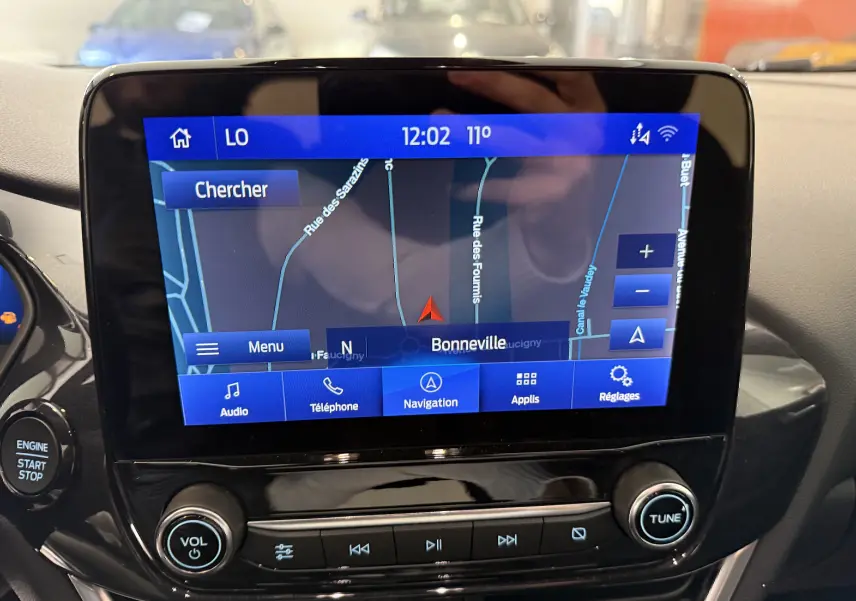 Écran tactile central du Ford Puma 2022 montrant la navigation GPS sur fond noir brillant avec commandes audio en dessous.