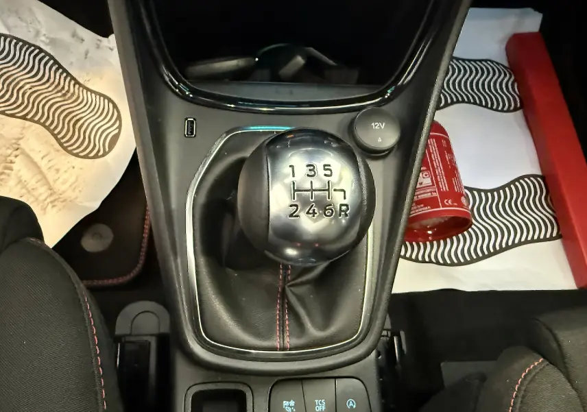 Vue plongeante sur le levier de vitesses manuel du Ford Puma noir agate, avec coutures rouges visibles sur la console centrale.