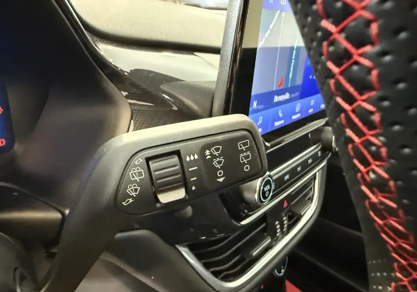 Gros plan sur la manette d’essuie-glace et le volant noir avec surpiqûres rouges dans le Ford Puma 2022.