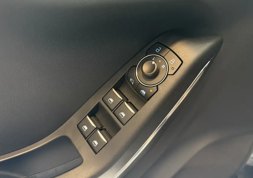 Gros plan sur les commandes de lève-vitres et réglage des rétroviseurs côté conducteur du Ford Puma noir Agate 2022.