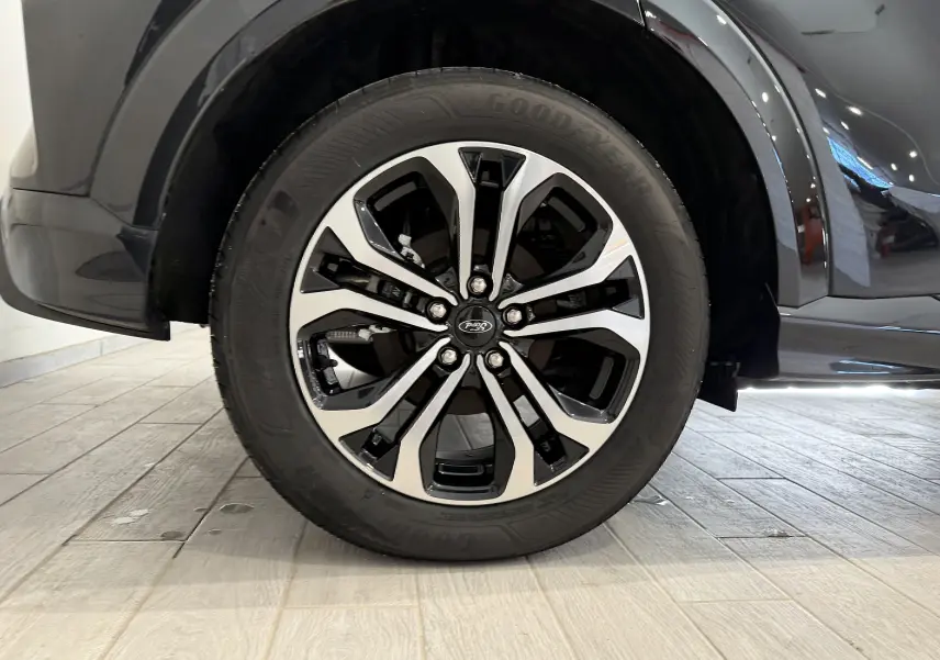 Gros plan sur la roue avant droite du Ford Puma noir Agate 2022 avec jante alliage bicolore et pneu Goodyear.