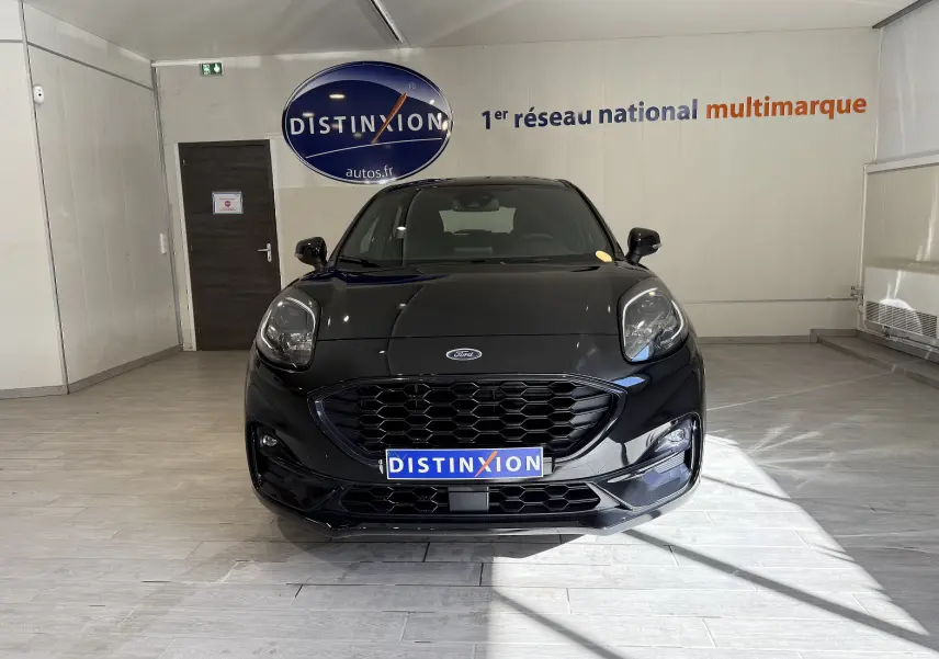 Vue frontale d'une Ford Puma noire Agate 2022 avec calandre hexagonale et phares LED dans un showroom.
