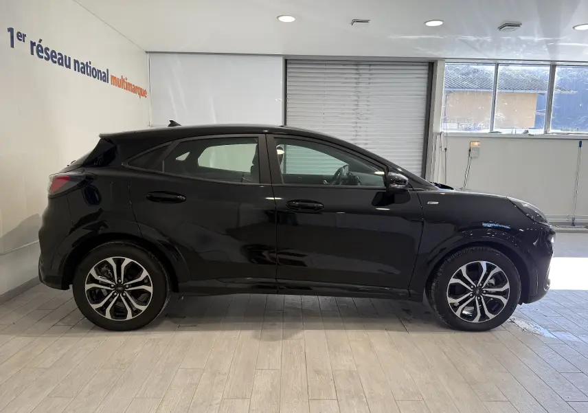 Vue de profil côté gauche du Ford Puma noir Agate 2022 avec jantes alliage et finition ST-Line en intérieur showroom.