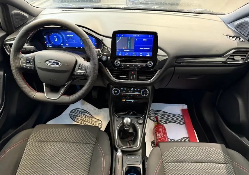 Vue intérieure avant du Ford Puma 1.0 EcoBoost MHEV 155ch ST-Line, tableau de bord noir avec écran tactile et boîte manuelle.