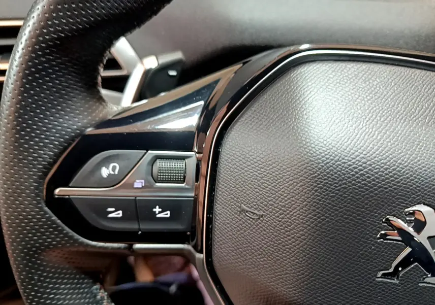 Gros plan sur le volant cuir noir du Peugeot 3008 GT 2023, avec commandes multifonctions intégrées à gauche.