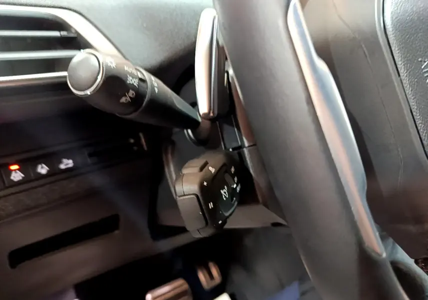 Gros plan sur la colonne de direction et commandes au volant du Peugeot 3008 noir 2023, intérieur moderne et épuré.