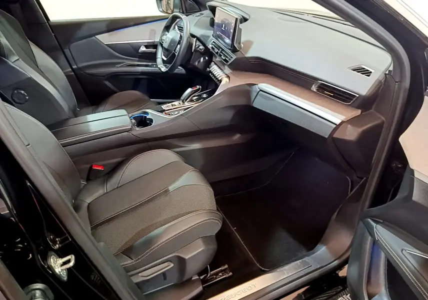 Intérieur côté passager du Peugeot 3008 noir 2023, avec tableau de bord moderne et sièges en tissu noir.