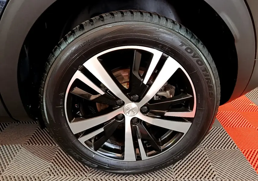 Gros plan sur la jante alliage bicolore noire et argentée d'un Peugeot 3008 noir, pneu Toyo visible.