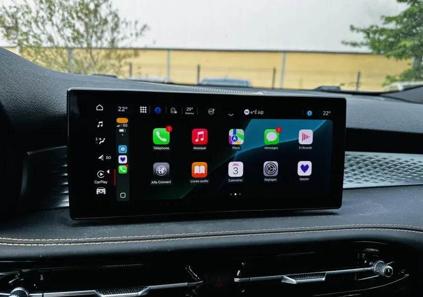 Écran tactile central de l'Alfa Romeo Tonale 2024 affichant Apple CarPlay, avec tableau de bord noir et surpiqûres beige.