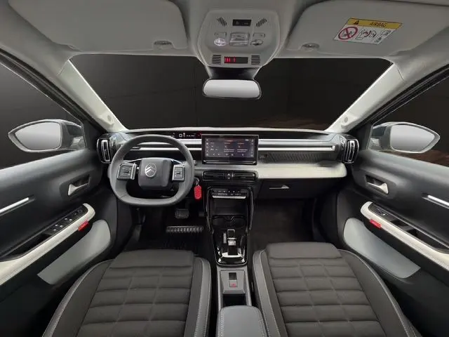 Vue intérieure avant de la Citroën C3 Aircross 2025 électrique, tableau de bord moderne avec écran tactile central et volant multifonction.