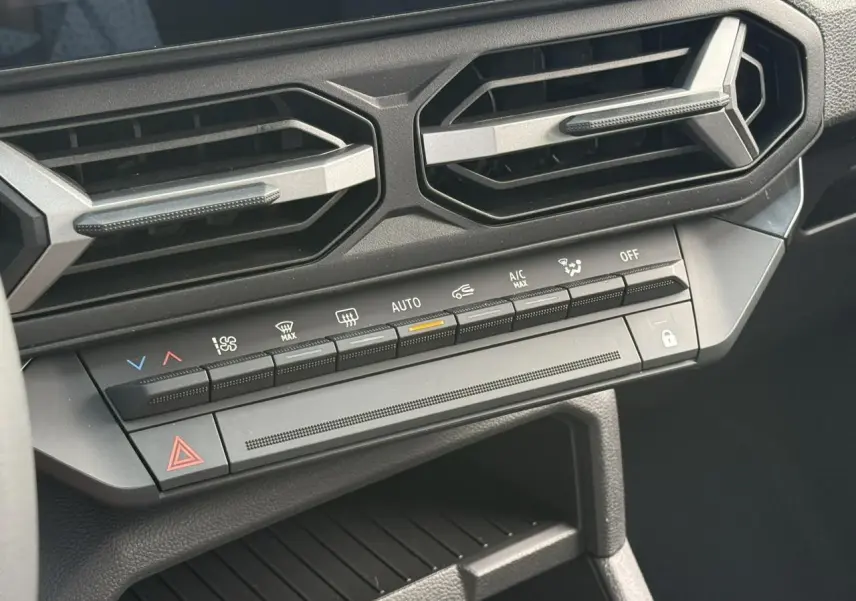 Détail du tableau de bord noir du Dacia Duster 2026 avec commandes climatisation et aérateurs hexagonaux.
