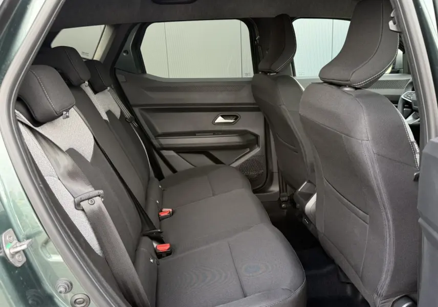 Vue latérale intérieure sur la banquette arrière noire du Dacia Duster Vert Cèdre avec ceinture de sécurité visible.