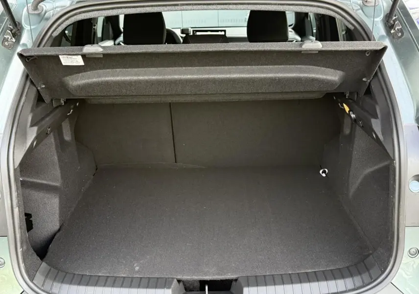 Coffre ouvert vu de l'arrière du Dacia Duster Vert Cèdre 2026, espace de chargement vide et tablette de séparation relevée.