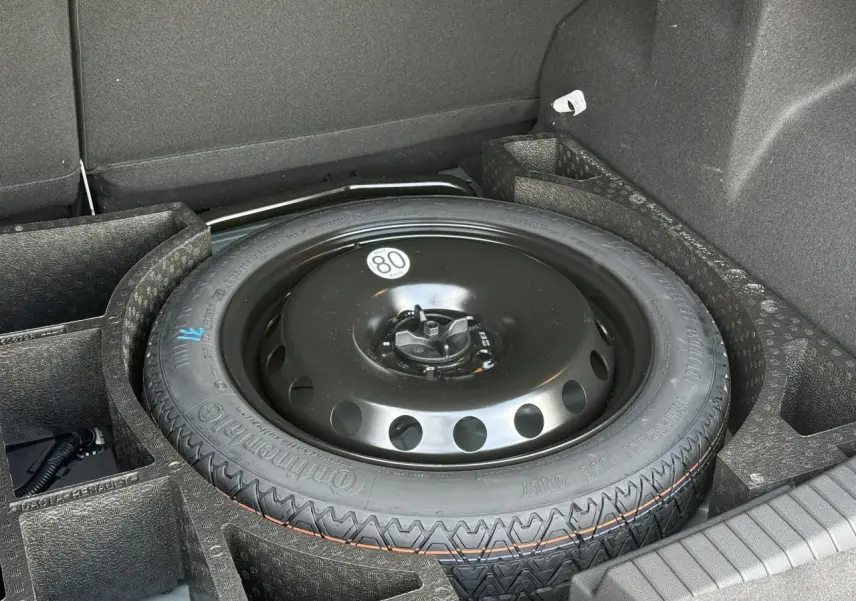 Gros plan sur la roue galette noire dans le coffre du Dacia Duster Vert Cèdre, version hybride 2026.