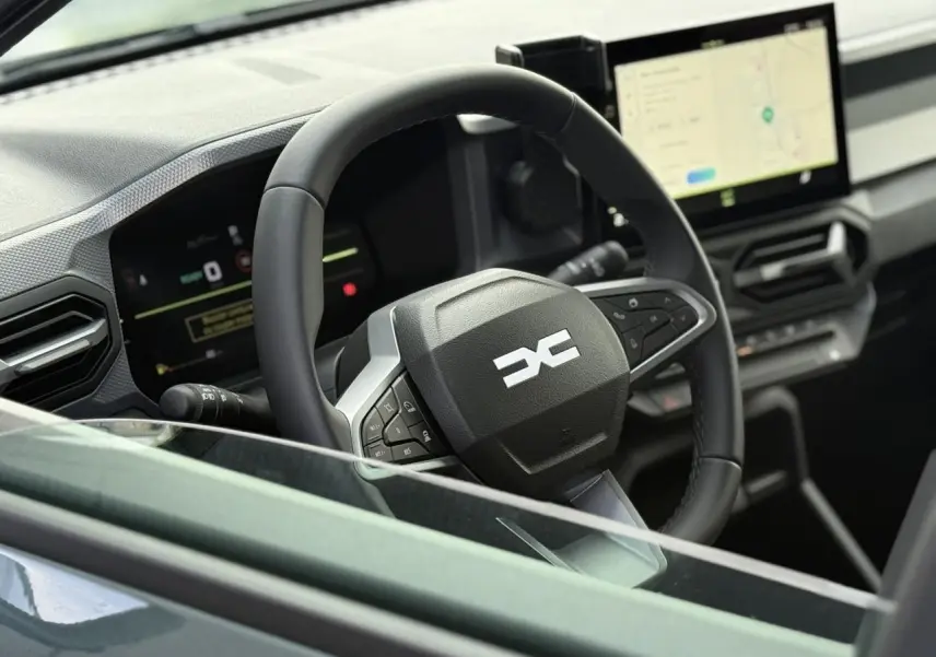 Vue rapprochée du volant et tableau de bord digital du Dacia Duster 2026, intérieur moderne et écran tactile.