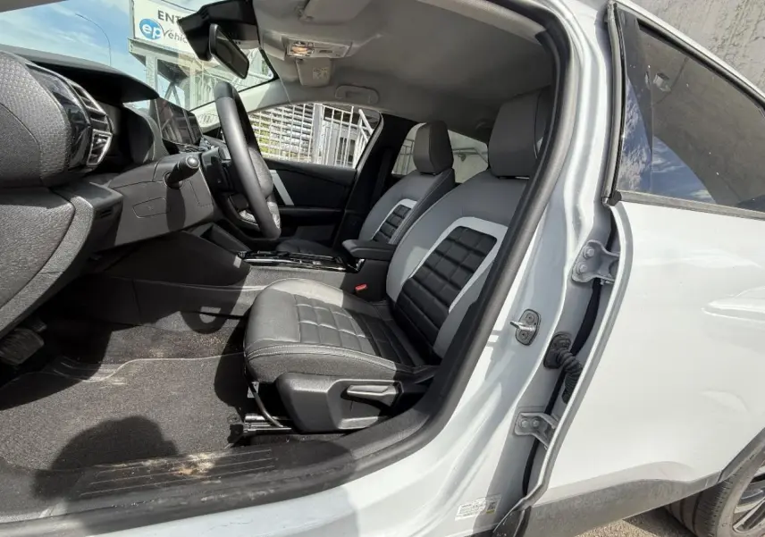 Vue intérieure côté conducteur de la Citroën C4 blanc okenite 2025, sièges bi-ton noir et gris avec console centrale visible.