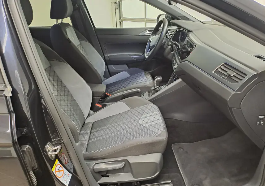 Vue intérieure côté conducteur du Volkswagen Taigo noir intense 2025, sièges tissu avec motifs géométriques et tableau de bord moderne.